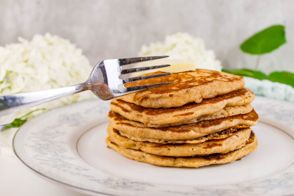 a fork cuts through a stack of homemade pancakes