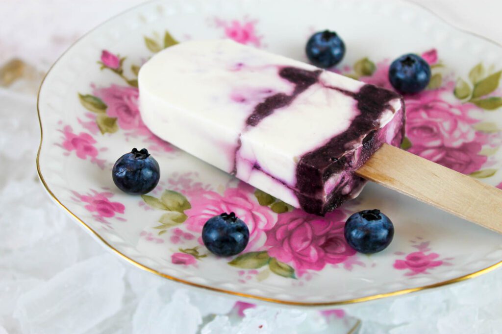 a homemade popsicle sits on a pink floral plate in the middle of a pile of ice cubes