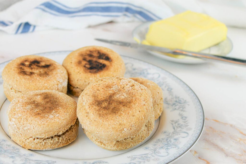 plate filled with golden brown muffins with a hunk of grass fed butter