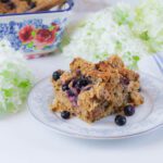 piece of french toast casserole with fresh milled bread sitting on a white and blue floral plate amongst some fresh cut flower