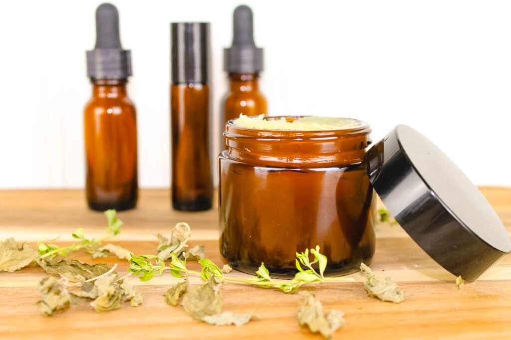 3 bottles of tinctures sit behind a jar of homemade salve