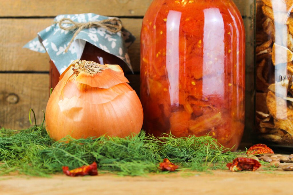large onion beside a jar of home canned tomatoes