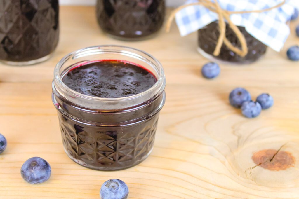 jar of freezer jam next to a bunch of fresh blueberries