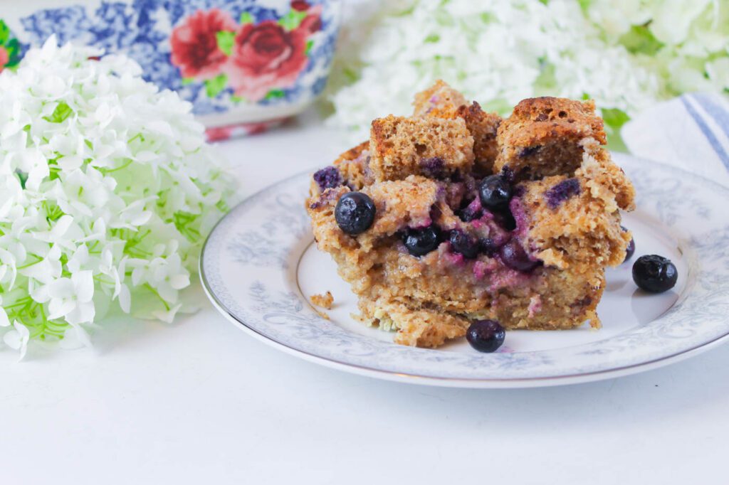piece of breakfast casserole served on a glass plate beside a floral baking dish