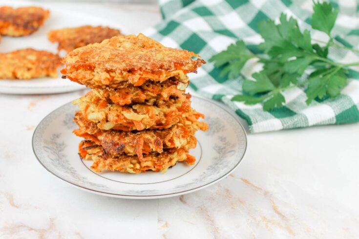 stack of zucchini fritters recipe with fresh milled flour sitting beside a green kitchen towel and fresh herbs