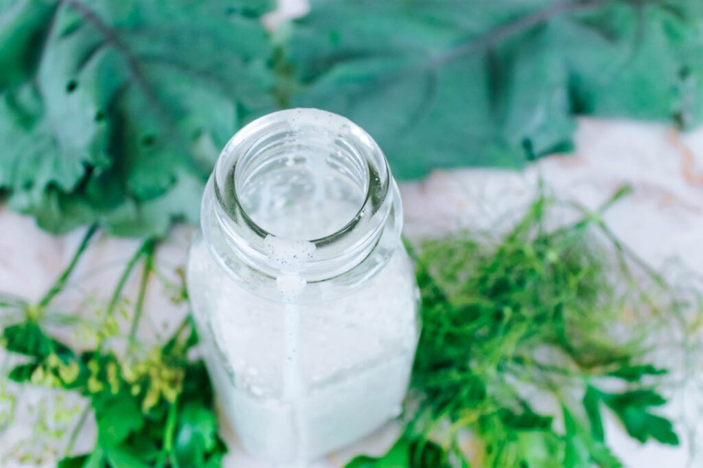 top view of a bottle of salad dressing next to fresh greens