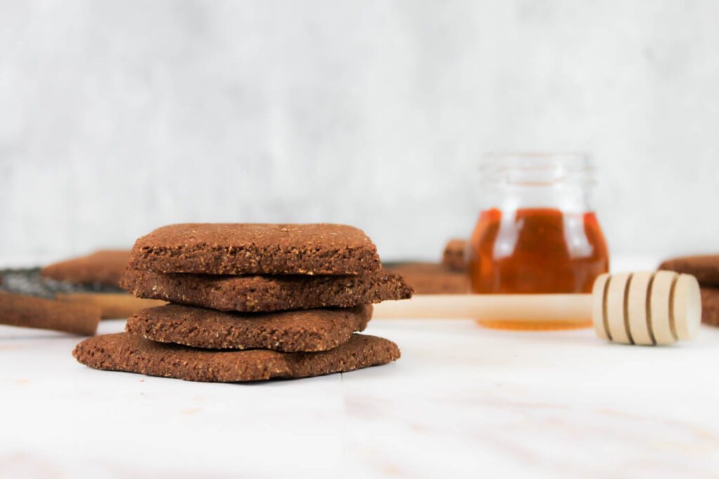 four graham crackers stacked on top of each other next to a jar of honey and a honey dipper
