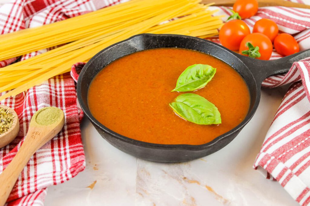 small cast iron skillet filled with spaghetti sauce with fresh tomatoes