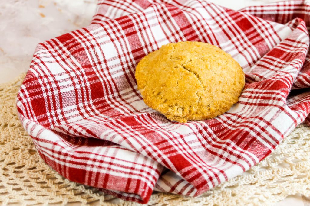 a small handheld apple pie sits on a plaid cloth napkin