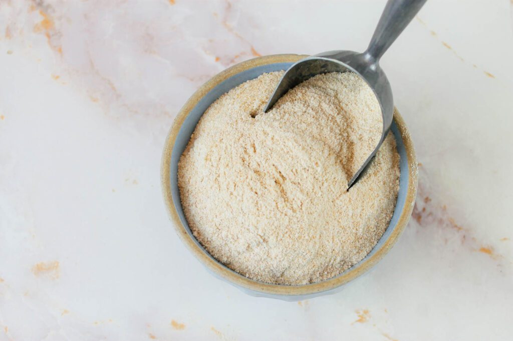 a bowl of fresh milled flour with a metal scoop inside