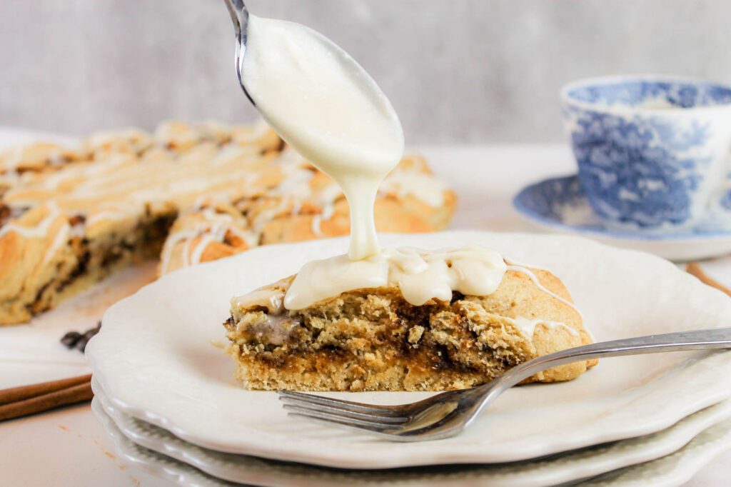 woman pours spoonful of glaze on top of cinnamon roll twist
