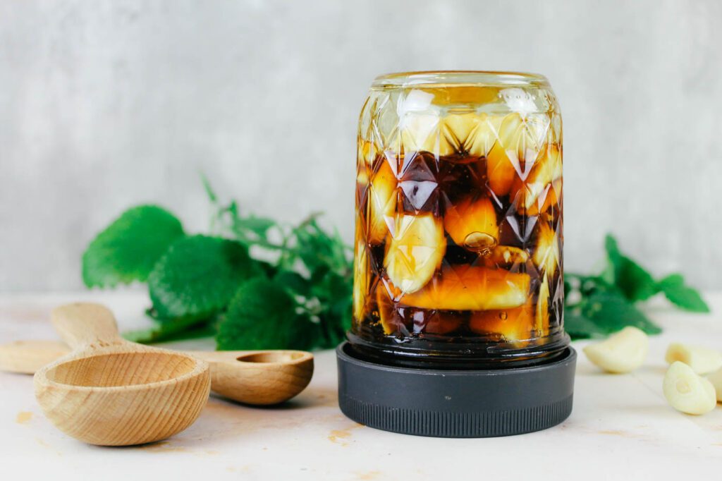 upside down jar filled with fermented garlic sitting beside wooden spoons
