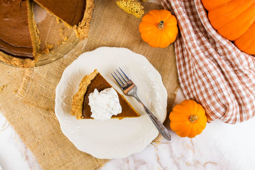 top view of a table filled with pumpkins, fall decor, plaid rags and pumpkin pie