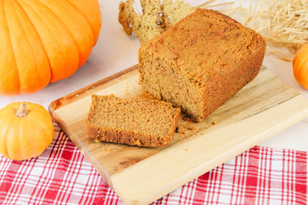 a sliced loaf of pumpkin bread on a cutting board in a kitchen