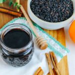 jar of elderberry syrup recipe next to dried berries, oranges and spices