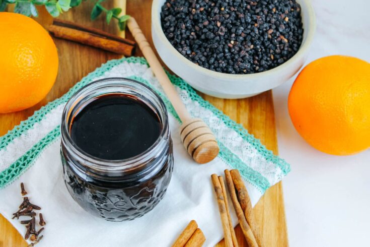 jar of elderberry syrup recipe next to dried berries, oranges and spices