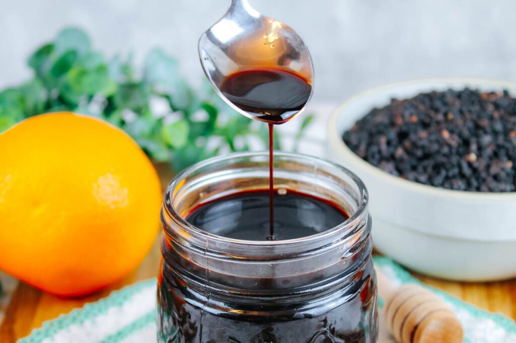 spoon pouring herbal syrup into jar