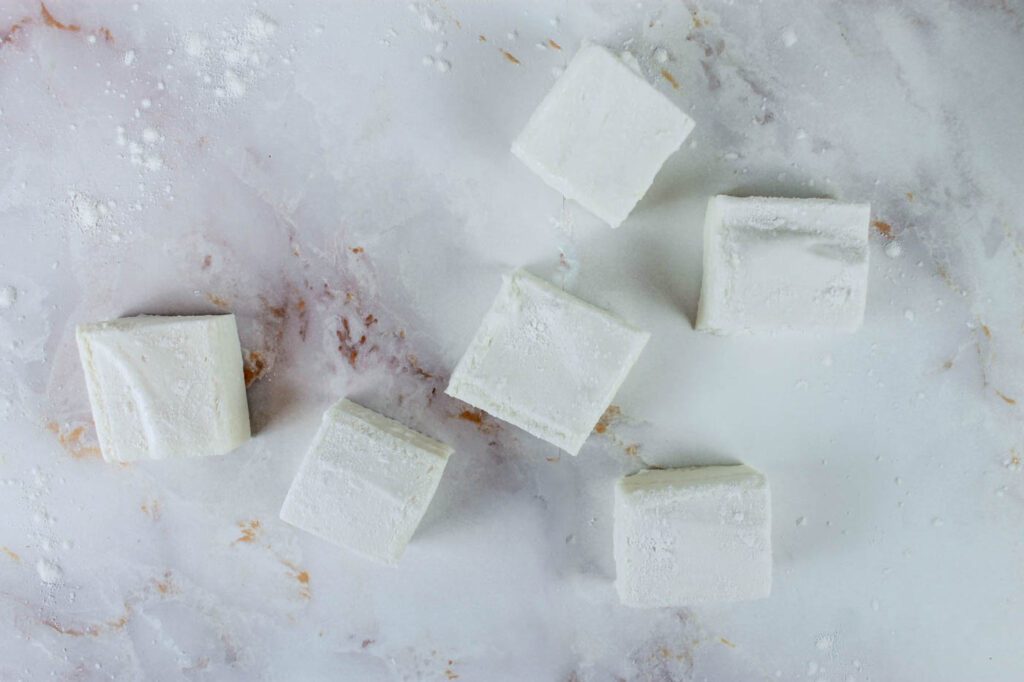 five square marshmallows sit on a marble countertop