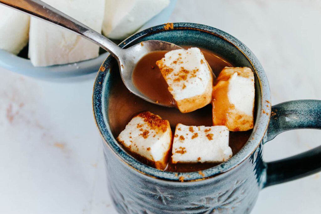woman scoops a marshmallow out of a mug