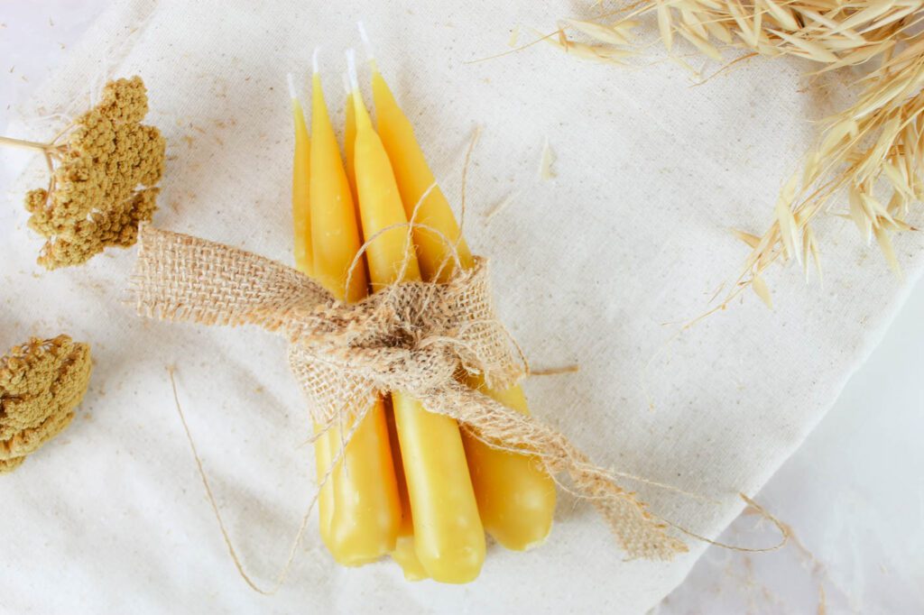 beeswax taper candles wrapped in a bundle on a white fabric