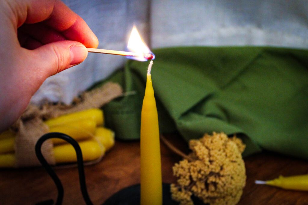 woman uses a match to light a candle
