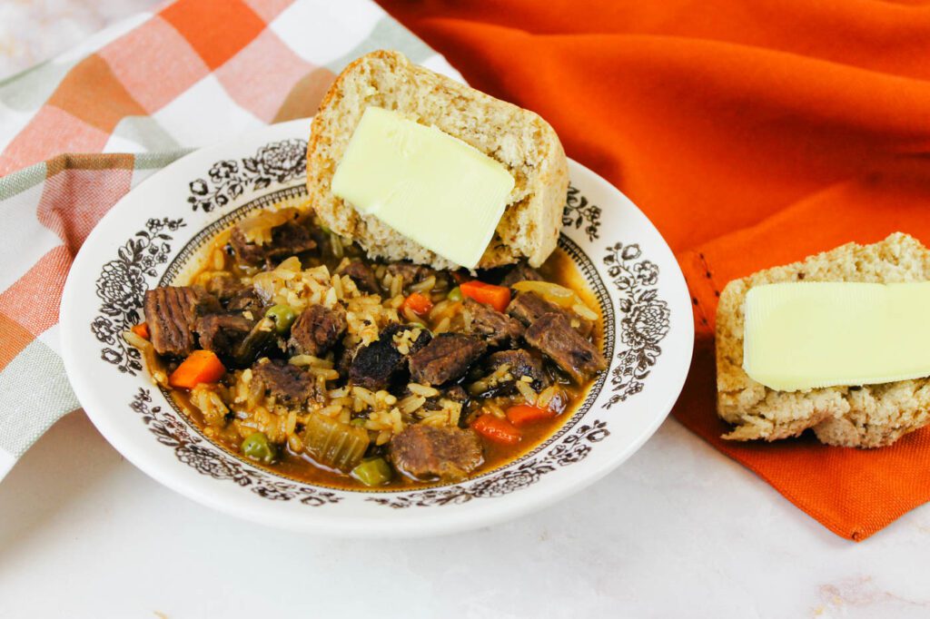bowl of soup with a buttered roll dipped into the broth