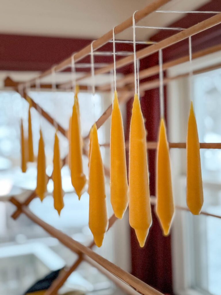 taper candles curing on drying rack