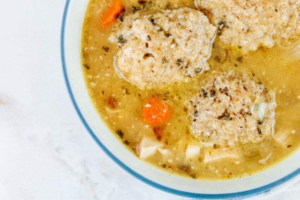 blue rimmed bowl filled with dumplings and chicken soup