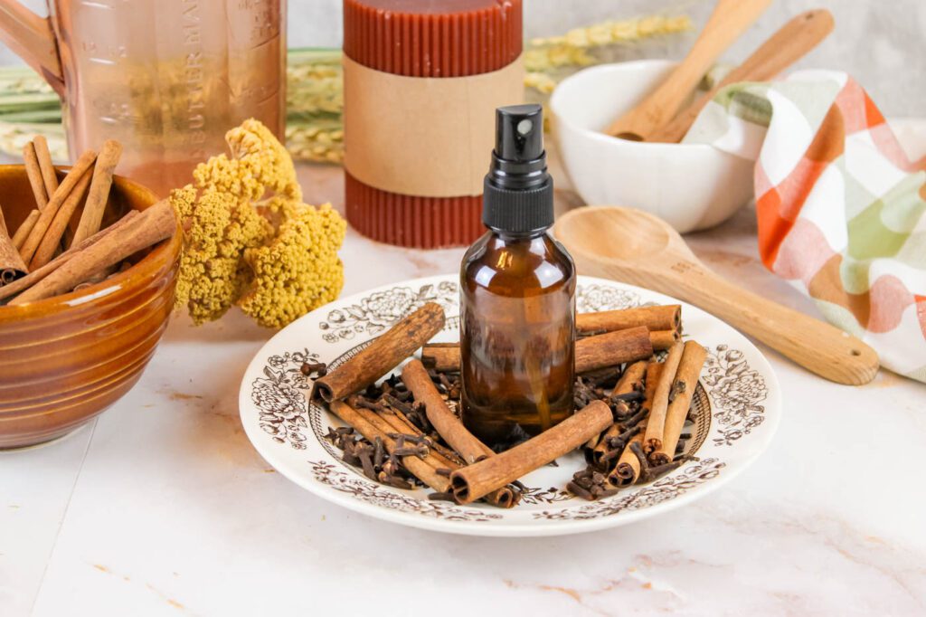 room spray sitting next to home decor, flowers and a candle