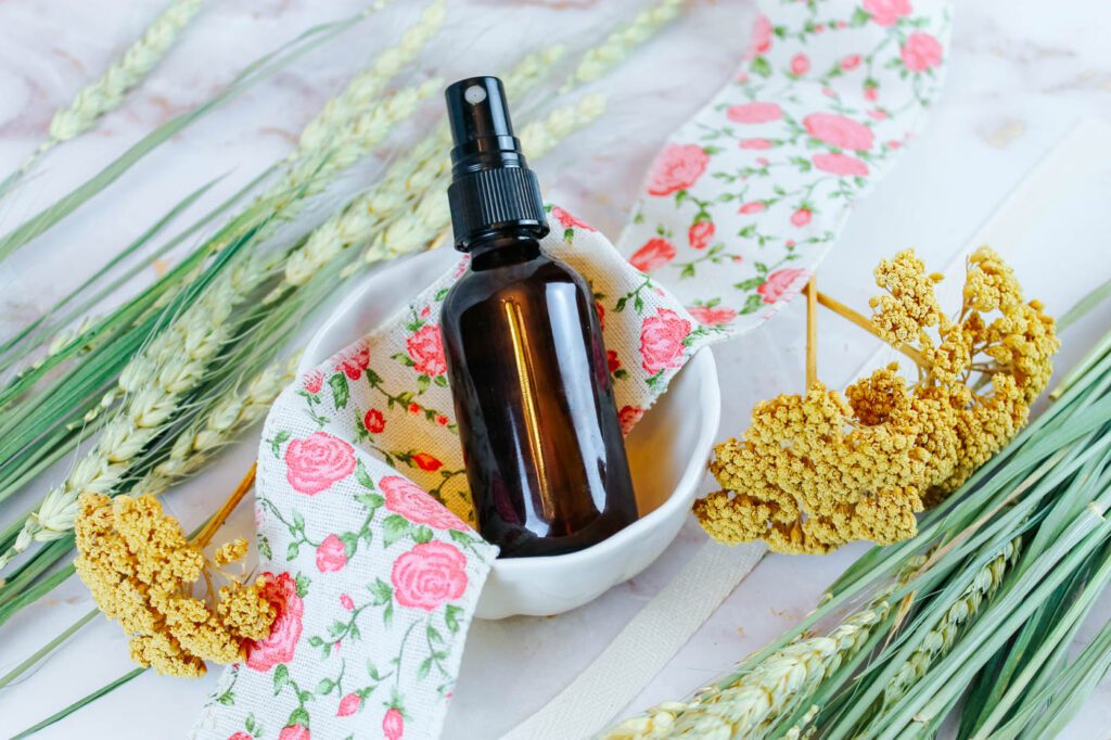 little white bowl with a spray bottle inside surrounded by floral ribbon and dried wheat and flowers