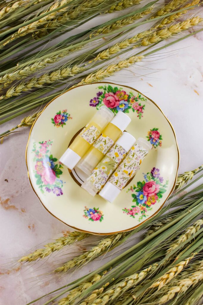 floral plate with tubes of lip balm surrounded by dried stalks of wheat