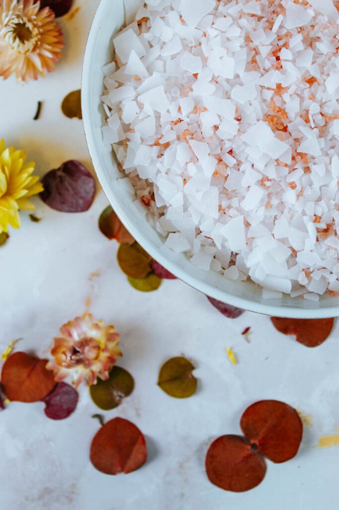 white bowl filled with flakes of magnesium sitting on table covered in petals