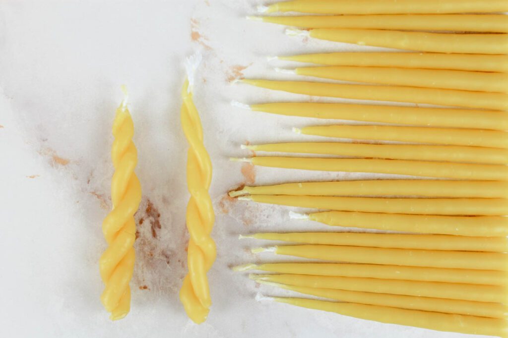 two twisted candles sitting beside a pile of small taper candles