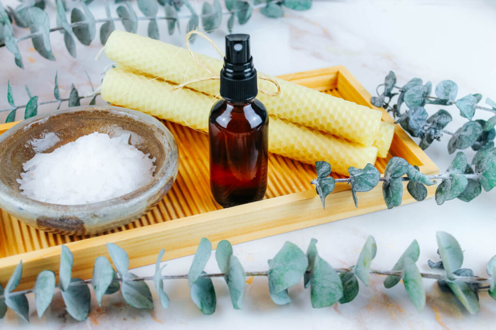 spray bottle filled with magnesium oil sitting next to candles and bath salt