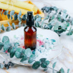 glass spray bottle filled with diy magnesium spray sitting on a floral plate